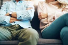 Body shot of couple sat on couch discussing no-fault divorce