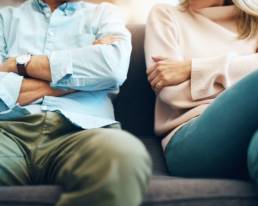 Body shot of couple sat on couch discussing no-fault divorce