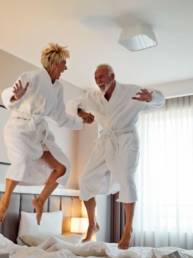 Happy elderly couple jumping on a bed