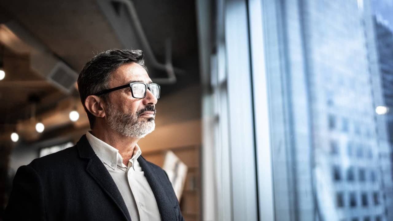Man wearing glasses looking out of window