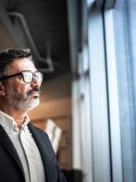 Man wearing glasses looking out of window