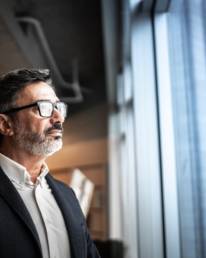 Man wearing glasses looking out of window