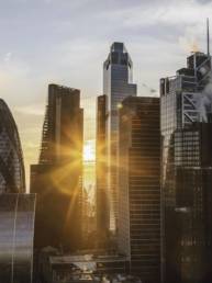 Sunrise over the City of London skyline with modern financial buildings and warm light between skyscrapers