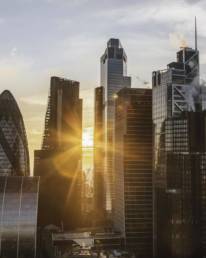 Sunrise over the City of London skyline with modern financial buildings and warm light between skyscrapers