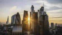 Sunrise over the City of London skyline with modern financial buildings and warm light between skyscrapers