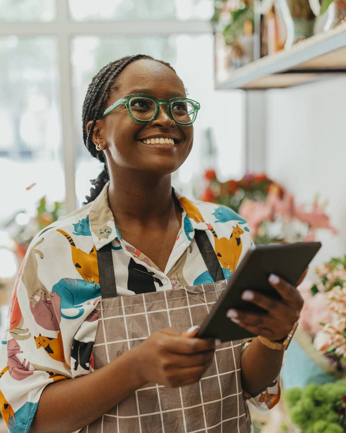 Florist holding a tablet in a flower shop while reviewing business finances for tax planning