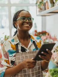 Florist holding a tablet in a flower shop while reviewing business finances for tax planning