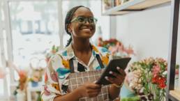 Florist holding a tablet in a flower shop while reviewing business finances for tax planning