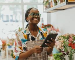 Florist holding a tablet in a flower shop while reviewing business finances for tax planning