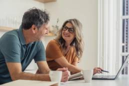 Couple checking financial documents and laptop while planning for tax year changes