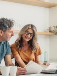 Couple looking at laptop and paperwork while discussing their finances at home