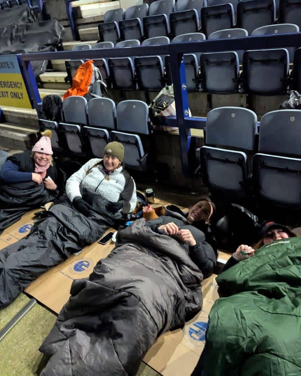 Amber River True Bearing colleagues in sleeping bags on cardboard inside Preston North End stadium during a charity sleep out.