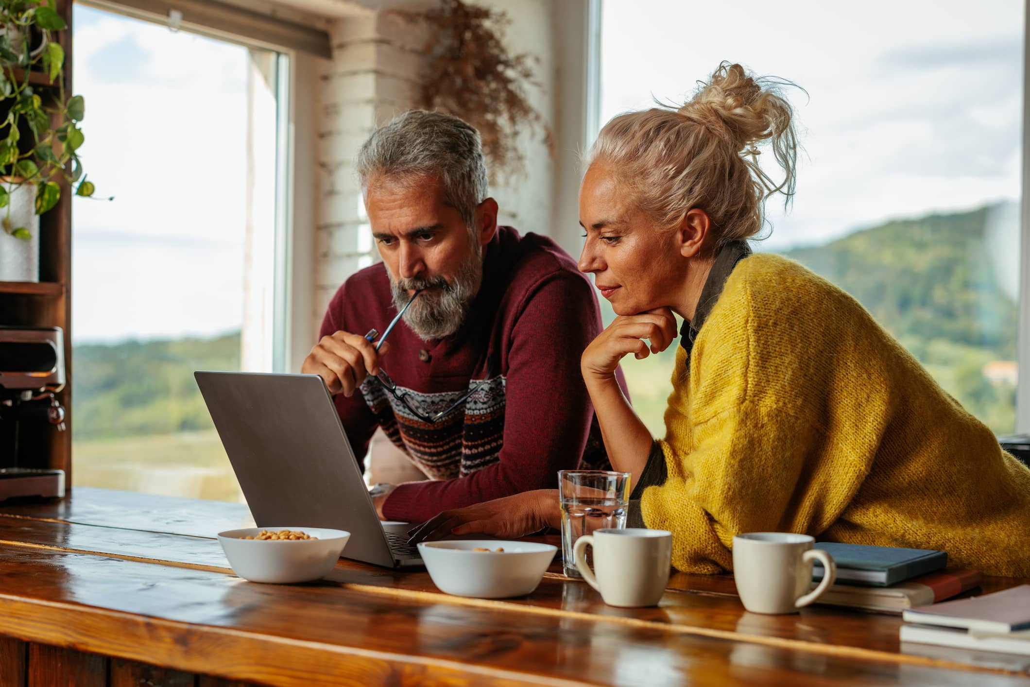 Middle-aged couple looking at a laptop together at home while discussing investment decisions during a market downturn.