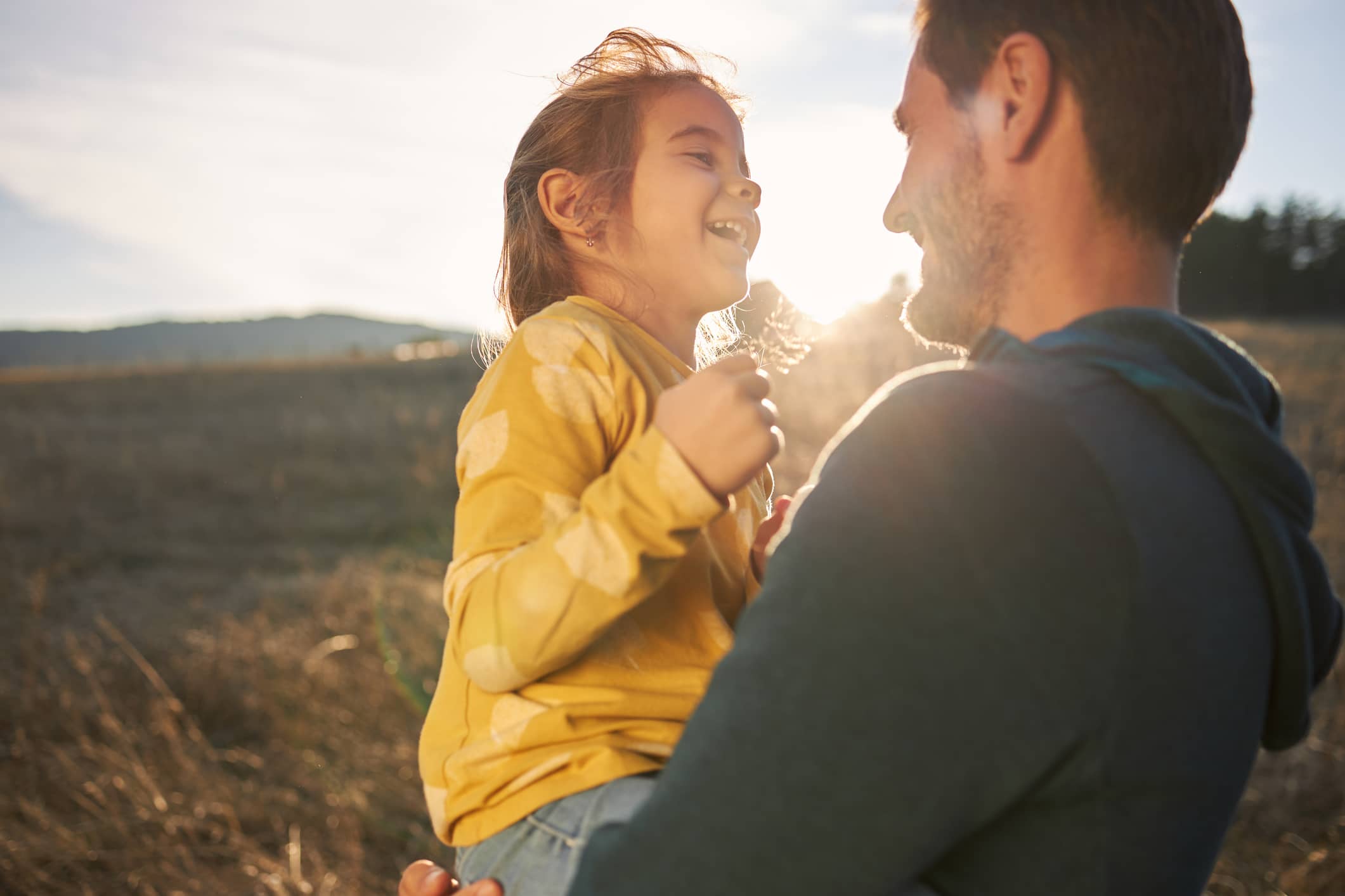 Parent holding a smiling child outdoors, representing long-term financial planning and building financial resilience.