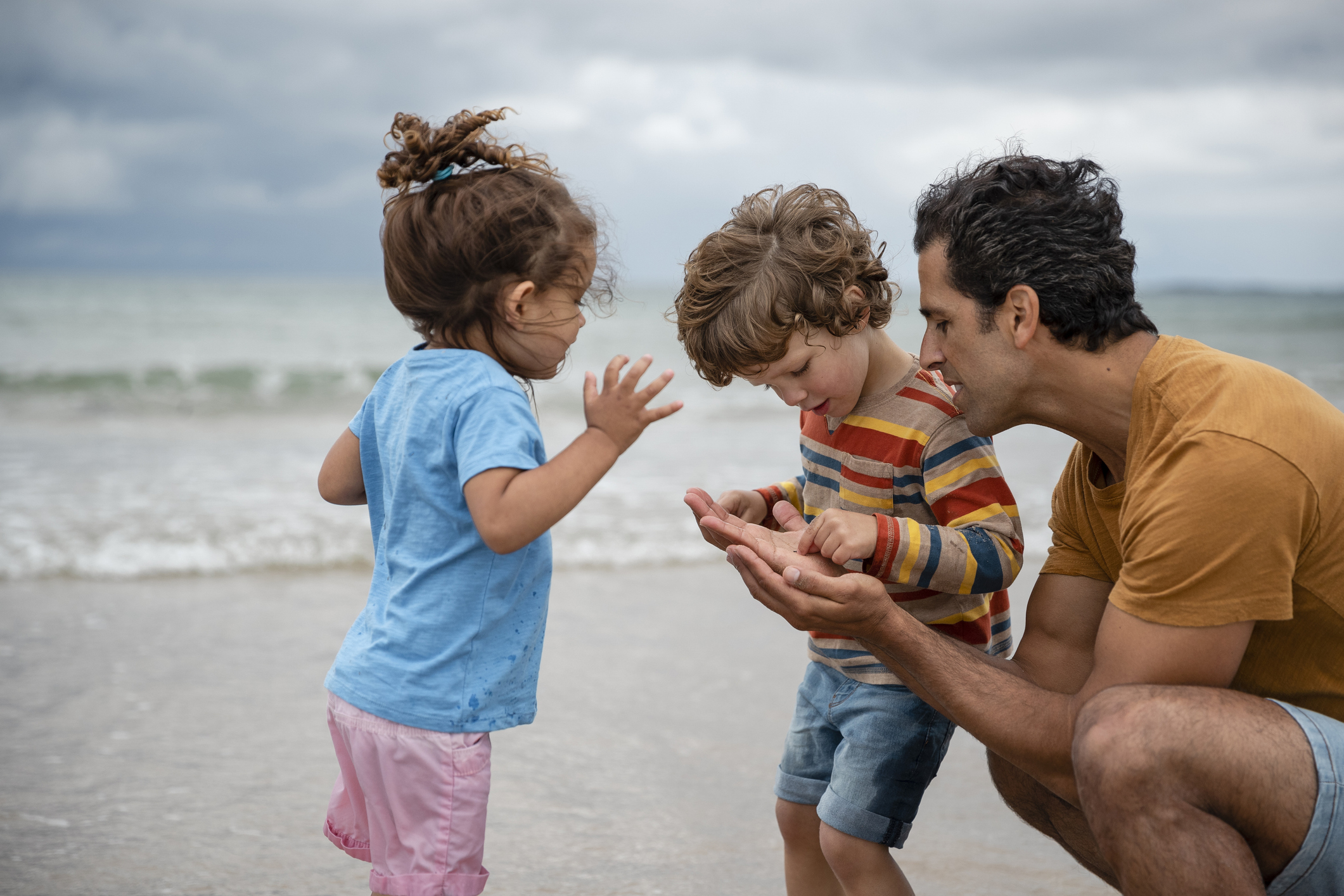 Parent and two children exploring together on a beach, representing long-term financial planning and family security.