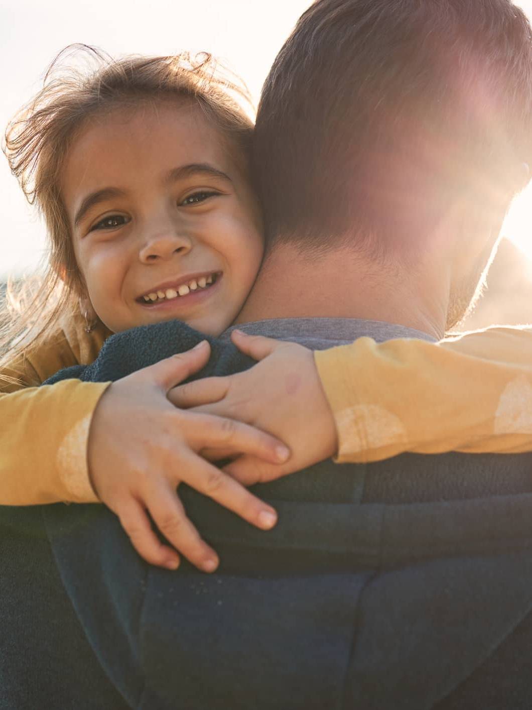 Young child hugging a parent, representing financial security and long-term family financial planning during uncertain times.