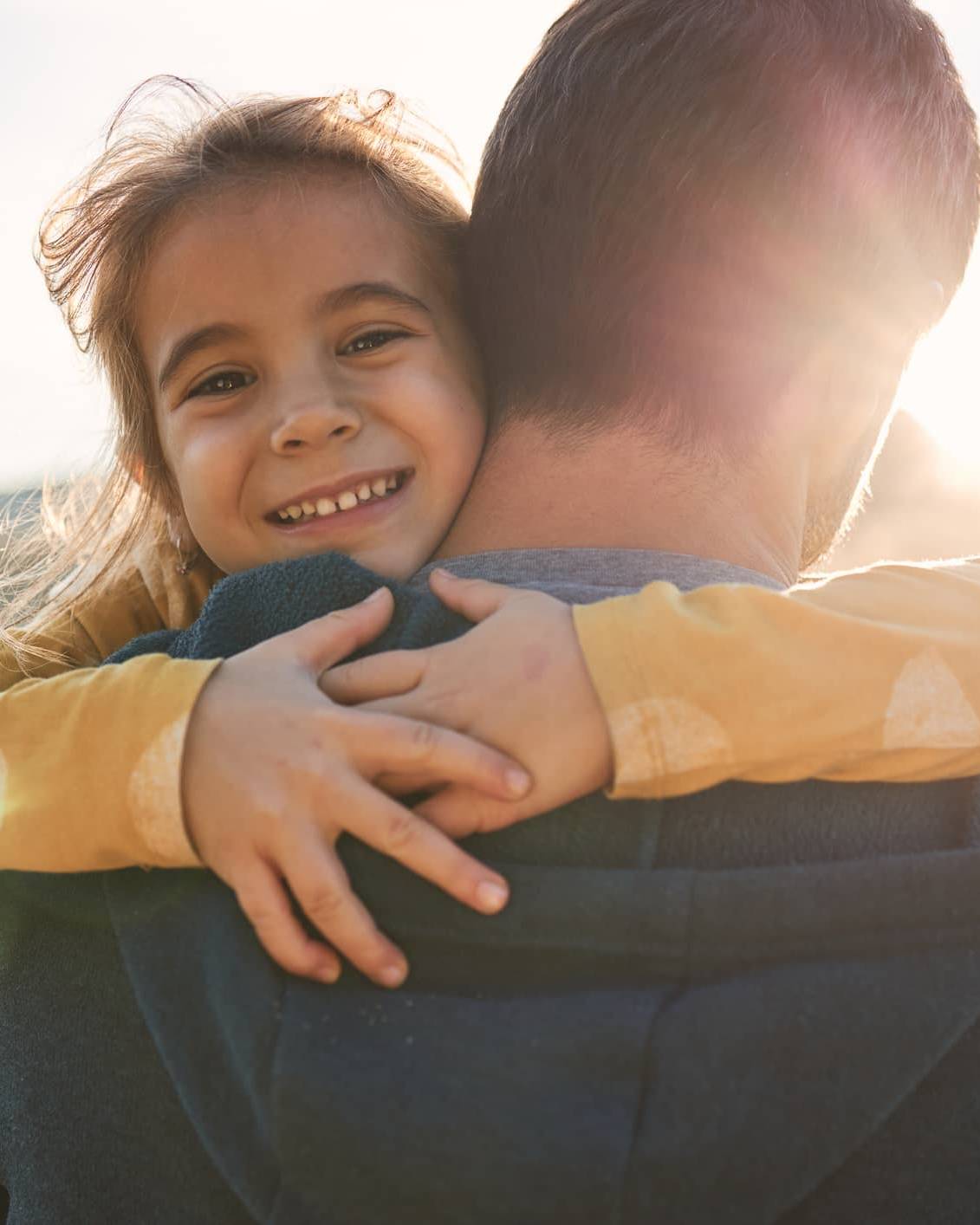Young child hugging a parent, representing financial security and long-term family financial planning during uncertain times.