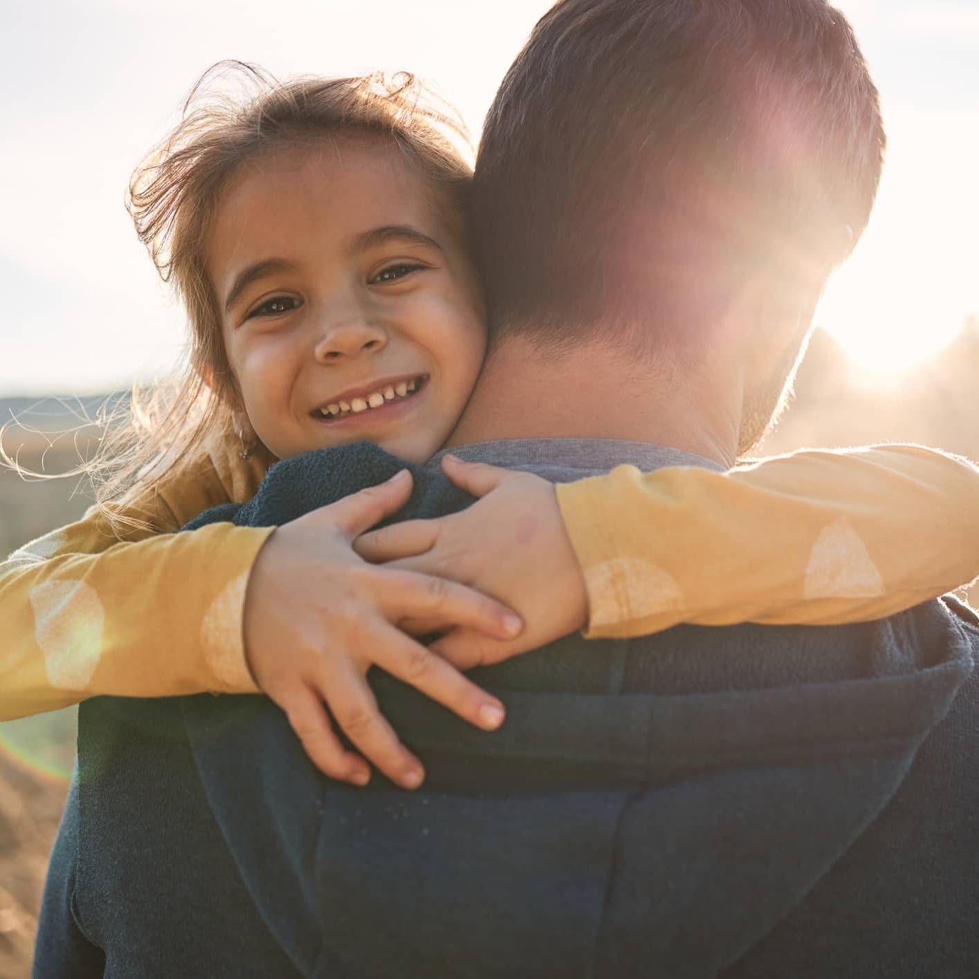 Young child hugging a parent, representing financial security and long-term family financial planning during uncertain times.