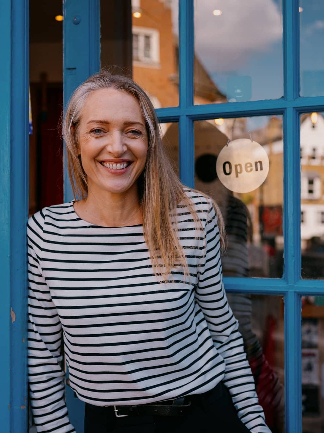 Business owner standing outside her shop illustrating financial planning for managing an irregular income
