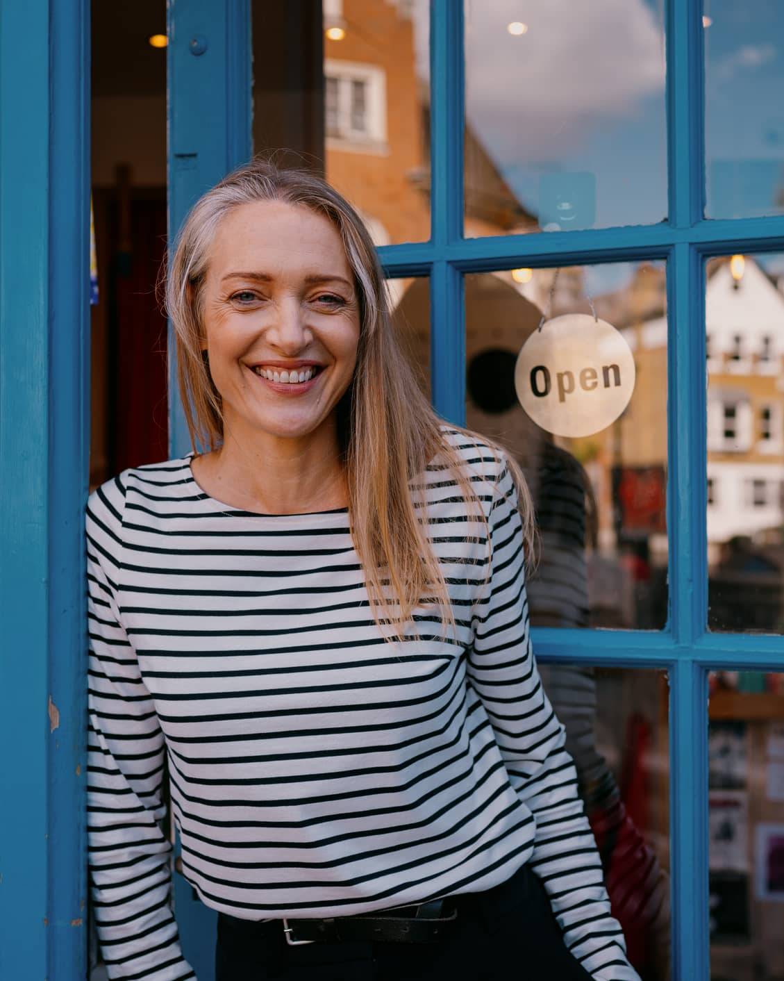 Business owner standing outside her shop illustrating financial planning for managing an irregular income