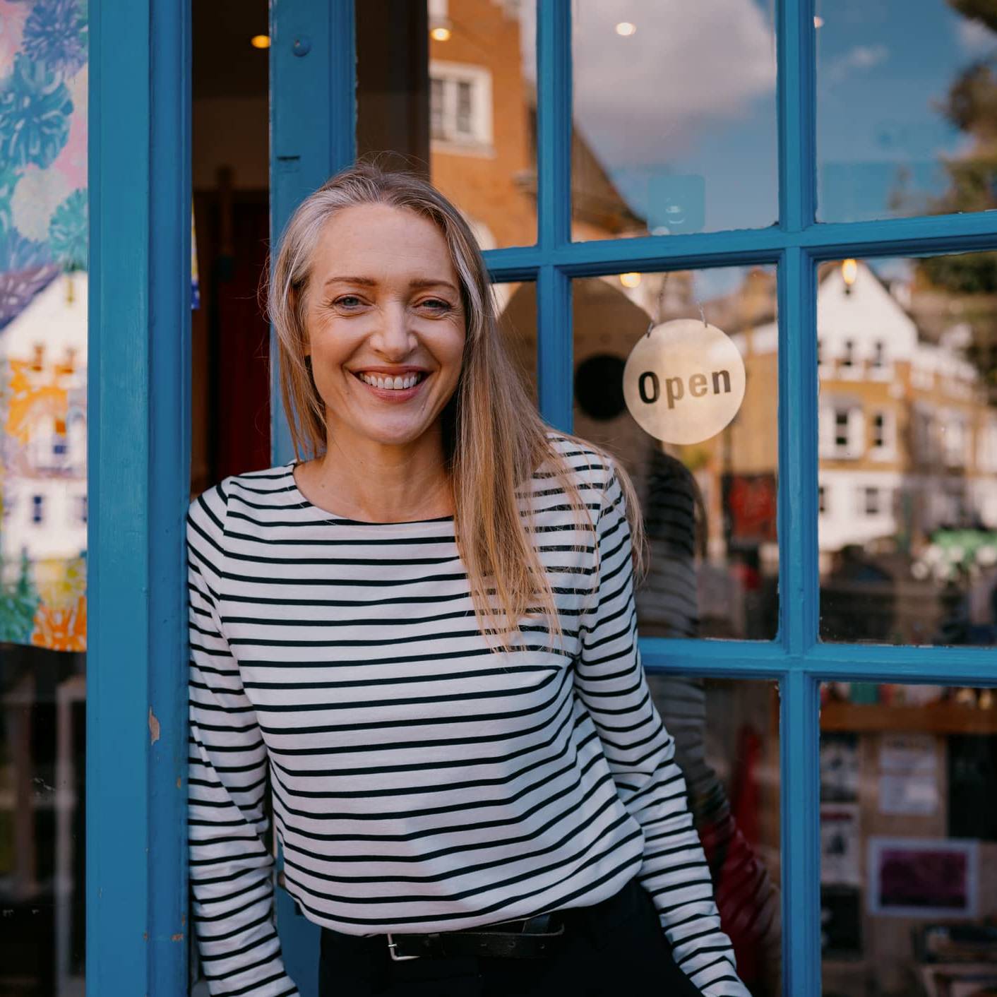 Business owner standing outside her shop illustrating financial planning for managing an irregular income