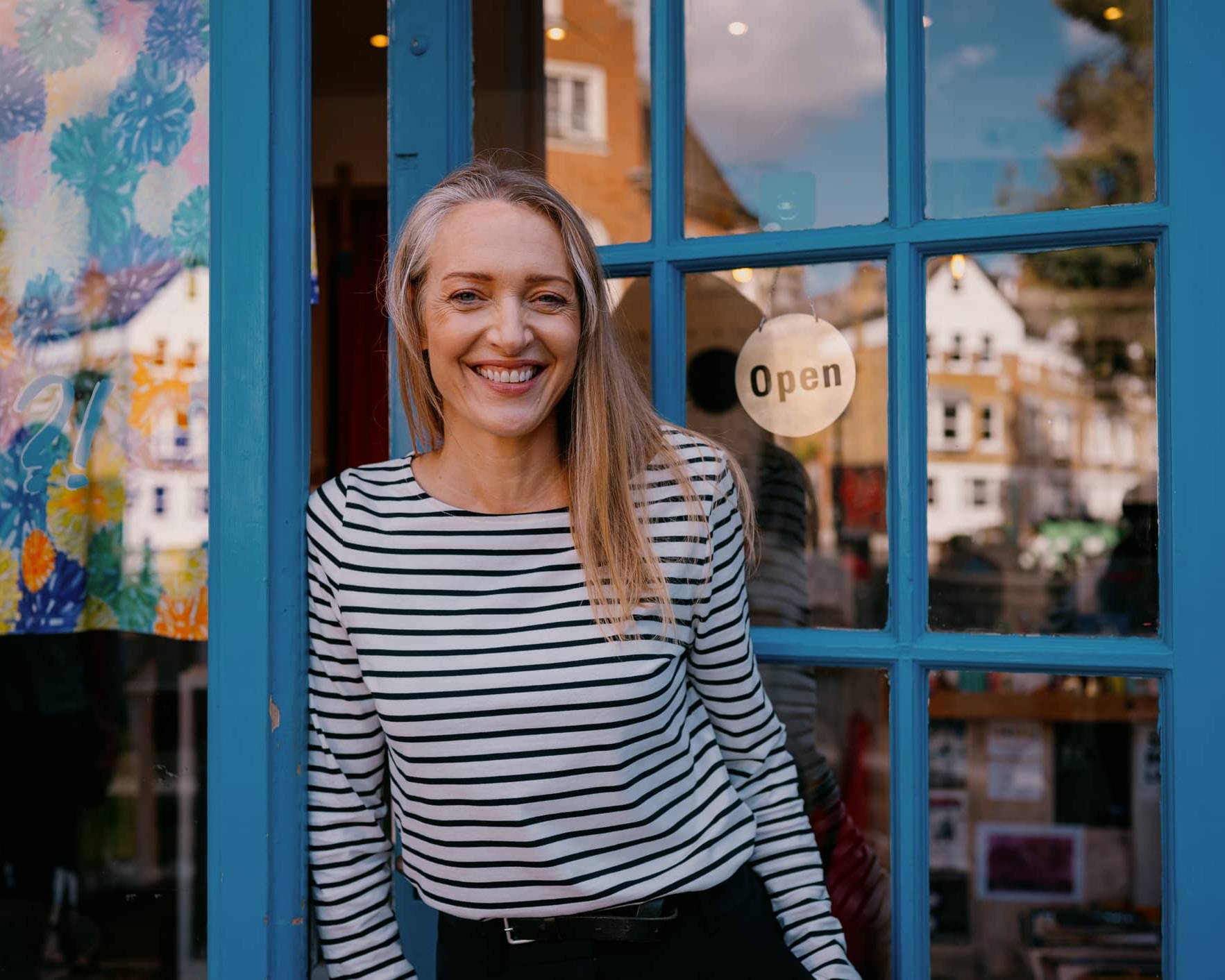 Business owner standing outside her shop illustrating financial planning for managing an irregular income