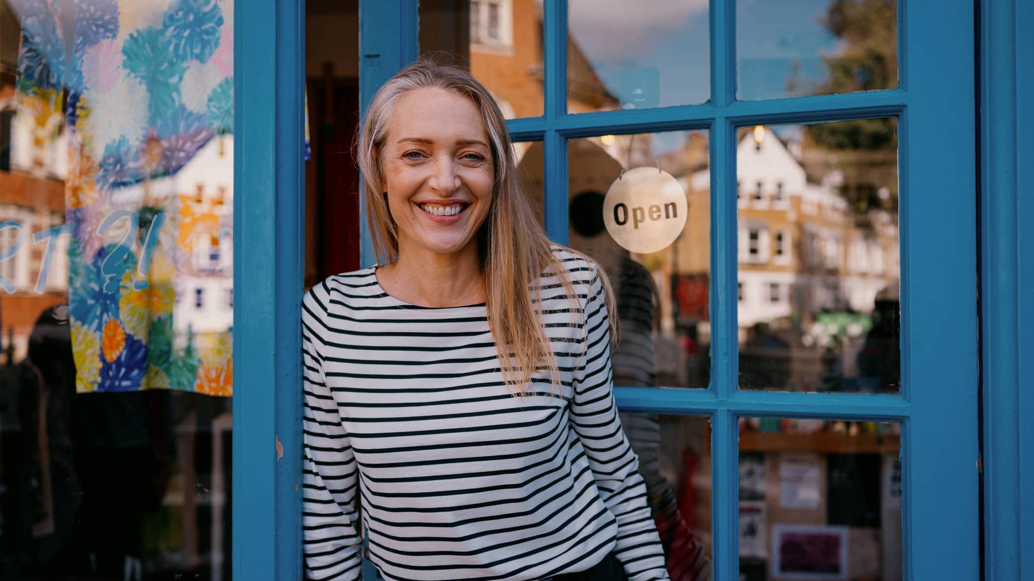 Business owner standing outside her shop illustrating financial planning for managing an irregular income