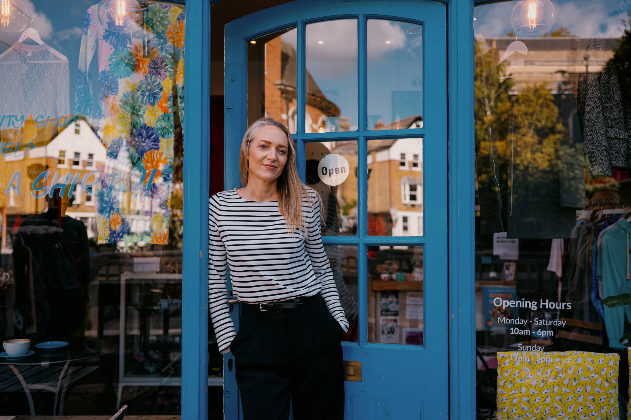 Small business owner smiling outside her shop representing financial planning for fluctuating business income Description A business owner outside her retail shop, illustrating the importance of financial planning, budgeting and cashflow management when dealing with irregular income. Used to accompany Amber River's article on five ways business owners can manage fluctuating income and build long-term financial resilience.
