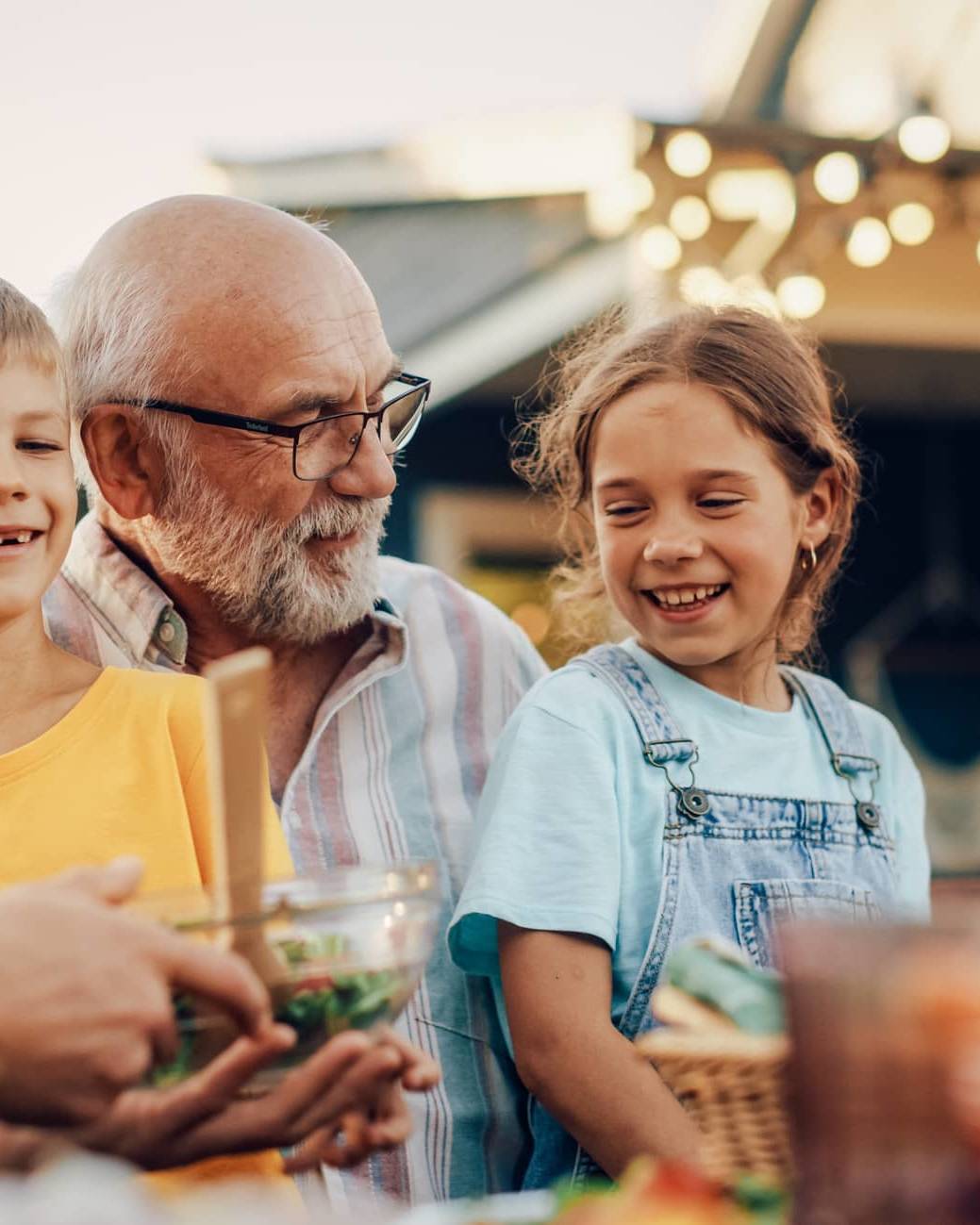 Three generations of a family enjoying a meal together outdoors, representing legacy planning and passing wealth between generations.