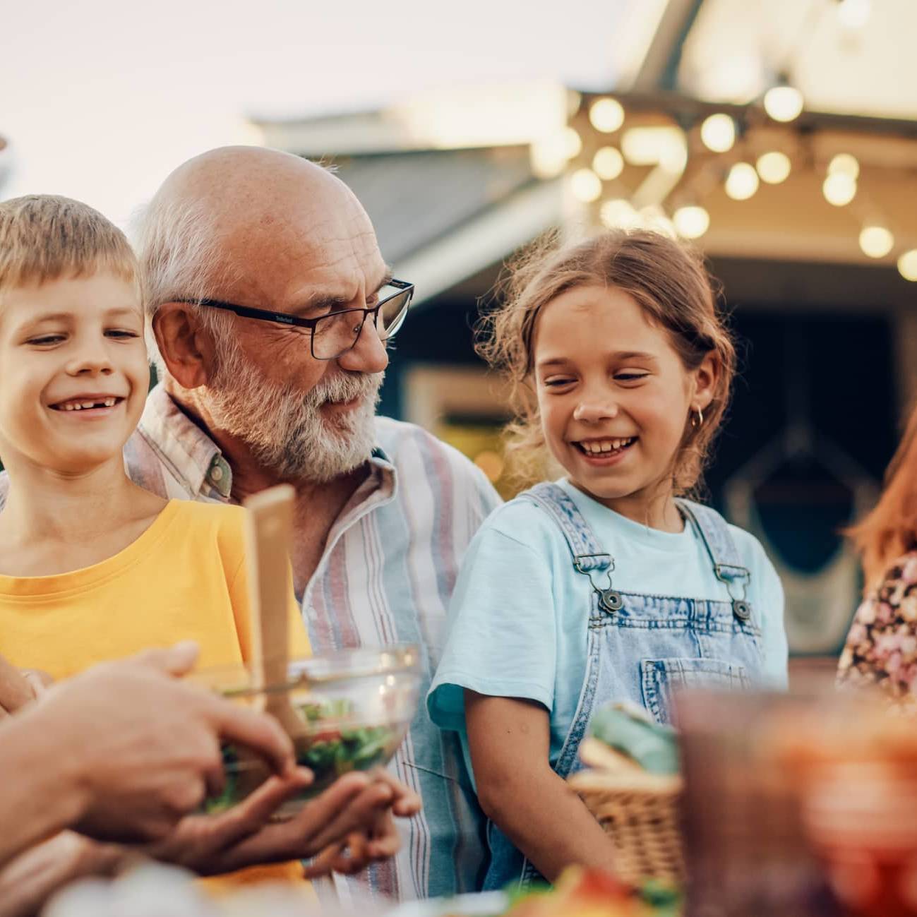 Three generations of a family enjoying a meal together outdoors, representing legacy planning and passing wealth between generations.