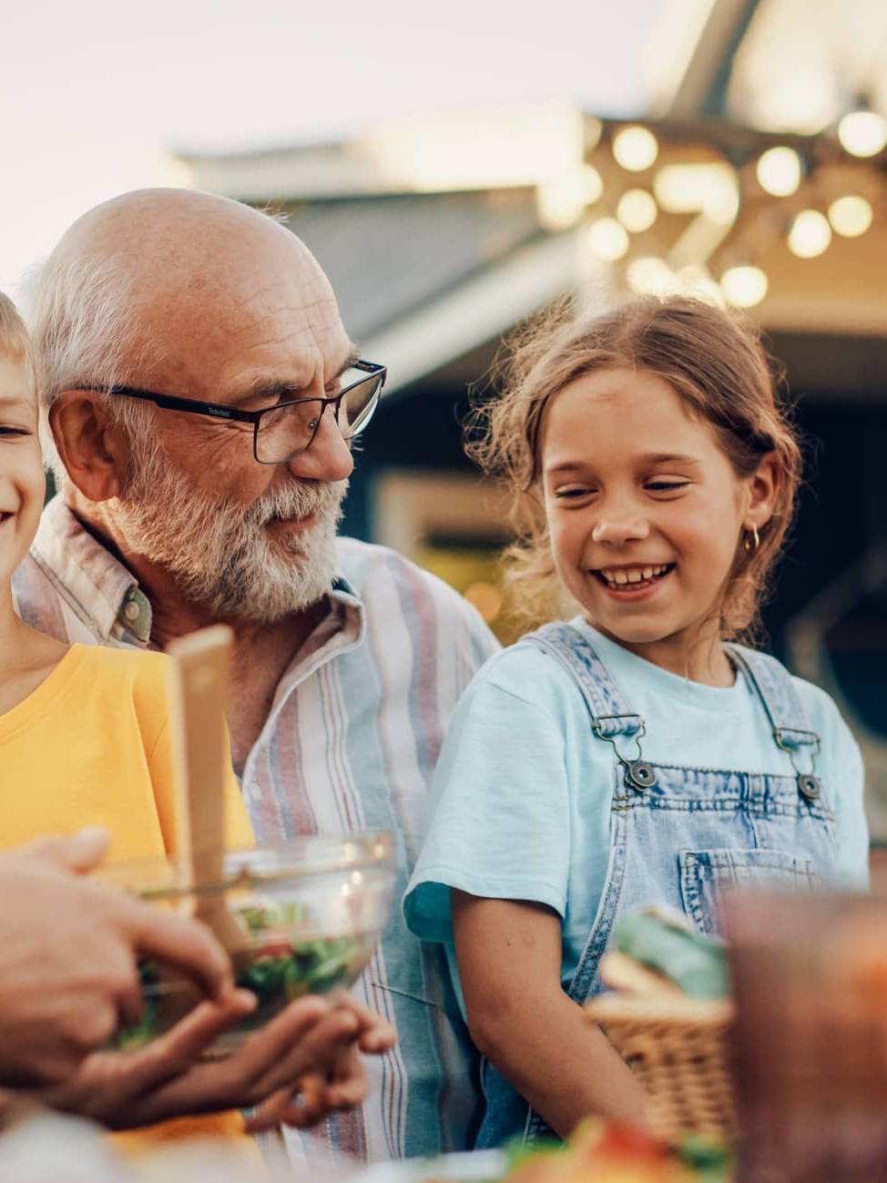 Three generations of a family enjoying a meal together outdoors, representing legacy planning and passing wealth between generations.