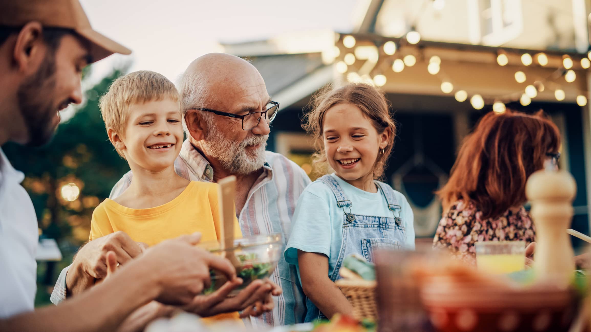 Three generations of a family enjoying a meal together outdoors, representing legacy planning and passing wealth between generations.