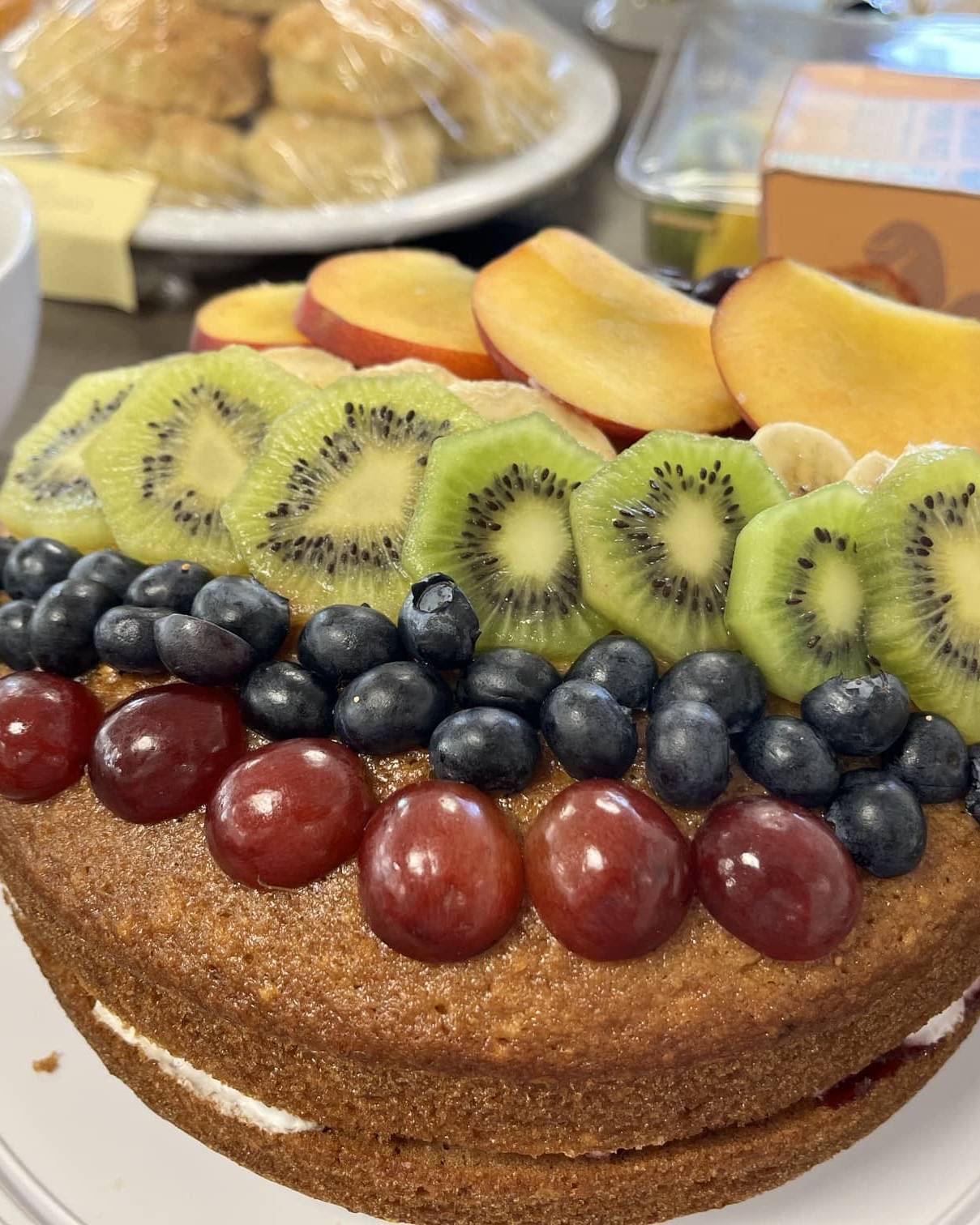 Fresh fruit-topped Victoria sponge cake prepared for Amber River East Anglia's Pride Month charity bake sale.