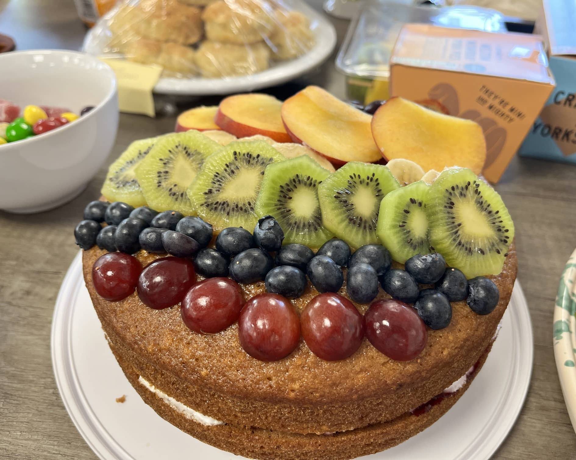 Fresh fruit-topped Victoria sponge cake prepared for Amber River East Anglia's Pride Month charity bake sale.