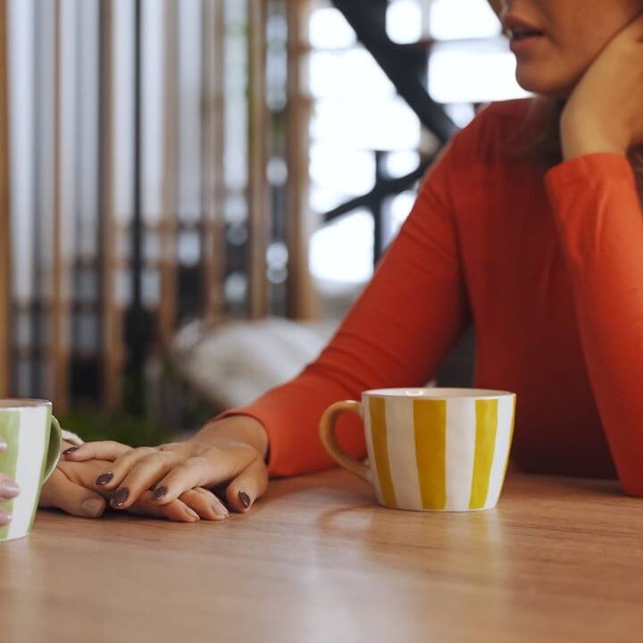 Mature woman talking with another person over coffee at a kitchen table
