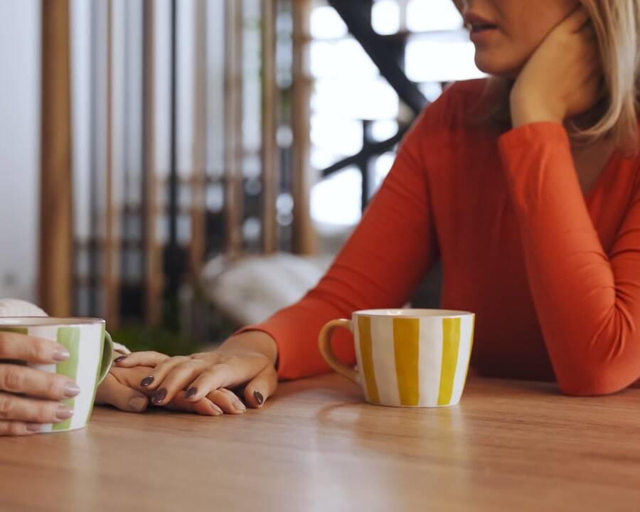 Mature woman talking with another person over coffee at a kitchen table