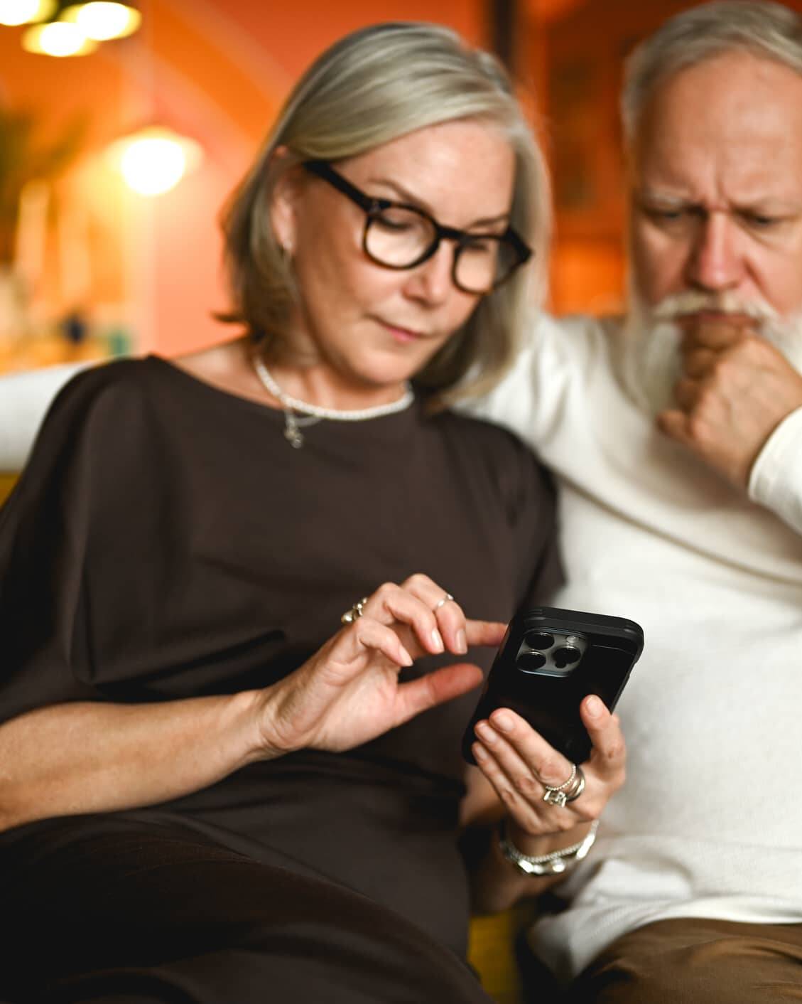Older couple looking at a smartphone while checking for signs of a potential financial scam