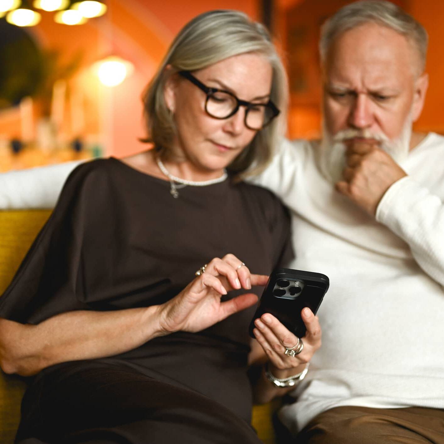 Older couple looking at a smartphone while checking for signs of a potential financial scam