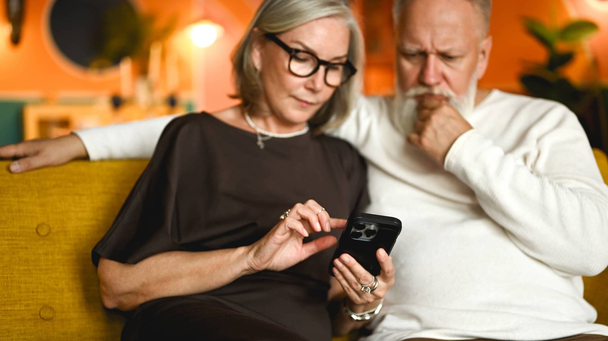 Older couple looking at a smartphone while checking for signs of a potential financial scam