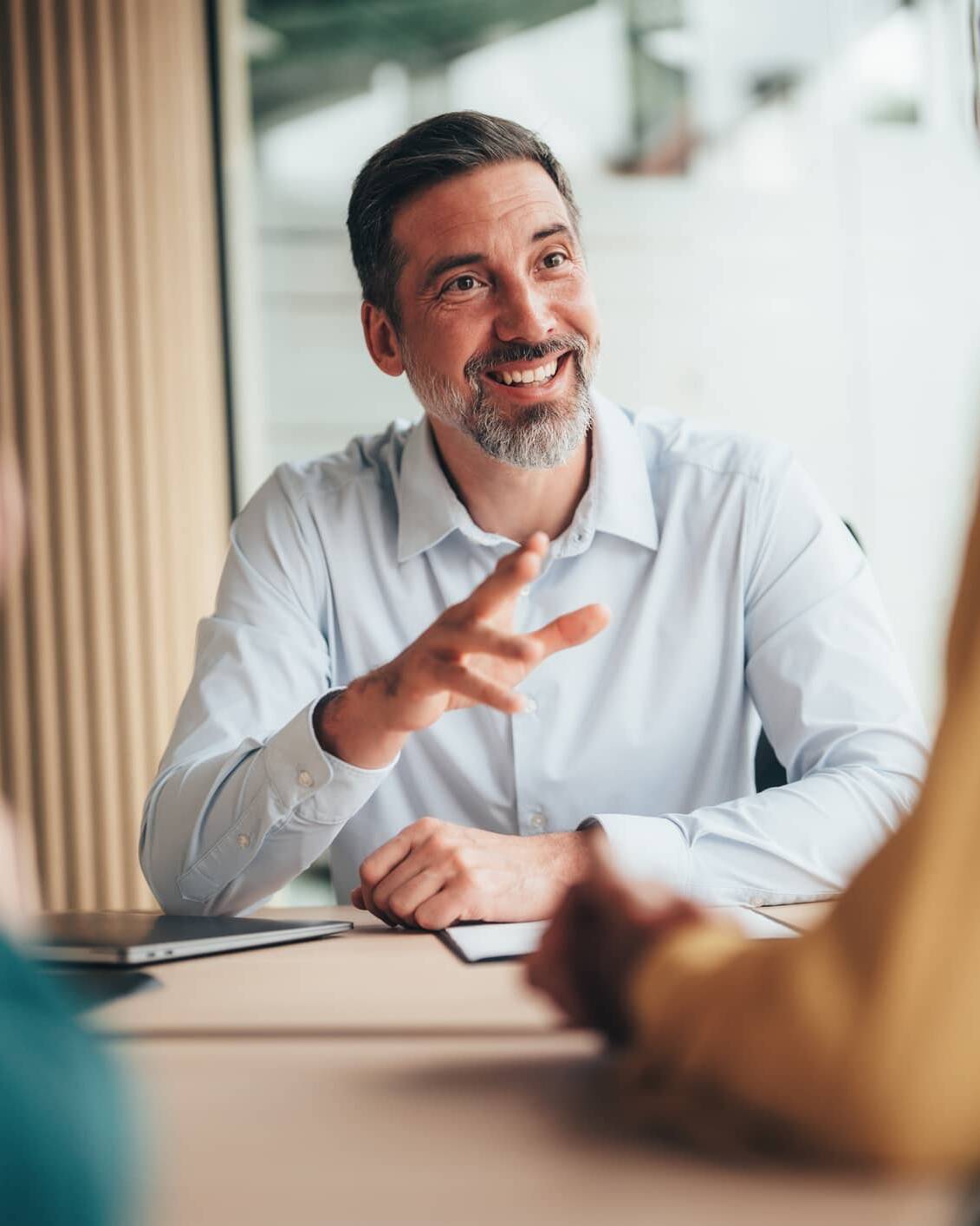 Financial adviser discussing financial planning with two clients during a meeting.