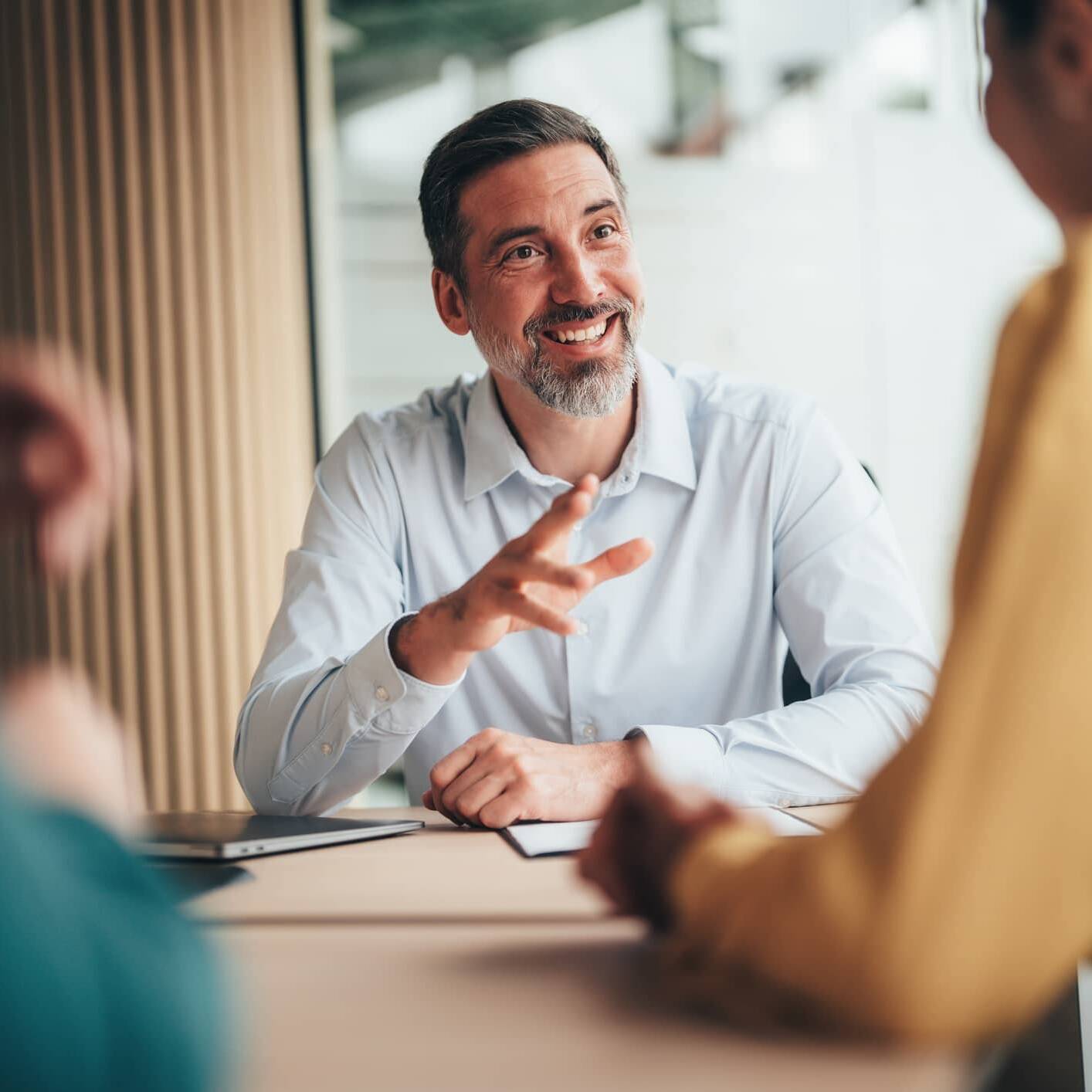 Financial adviser discussing financial planning with two clients during a meeting.