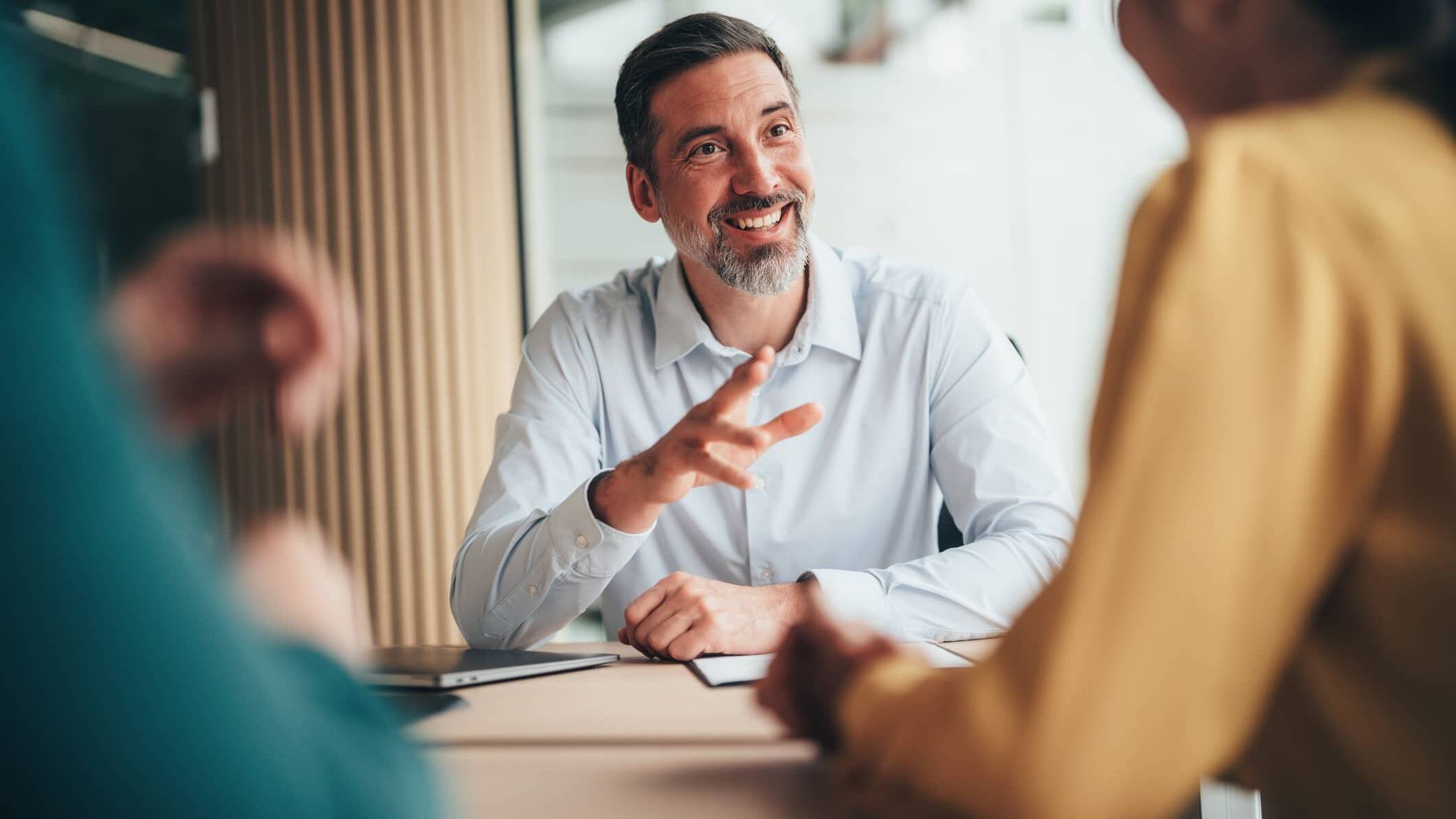 Financial adviser discussing financial planning with two clients during a meeting.