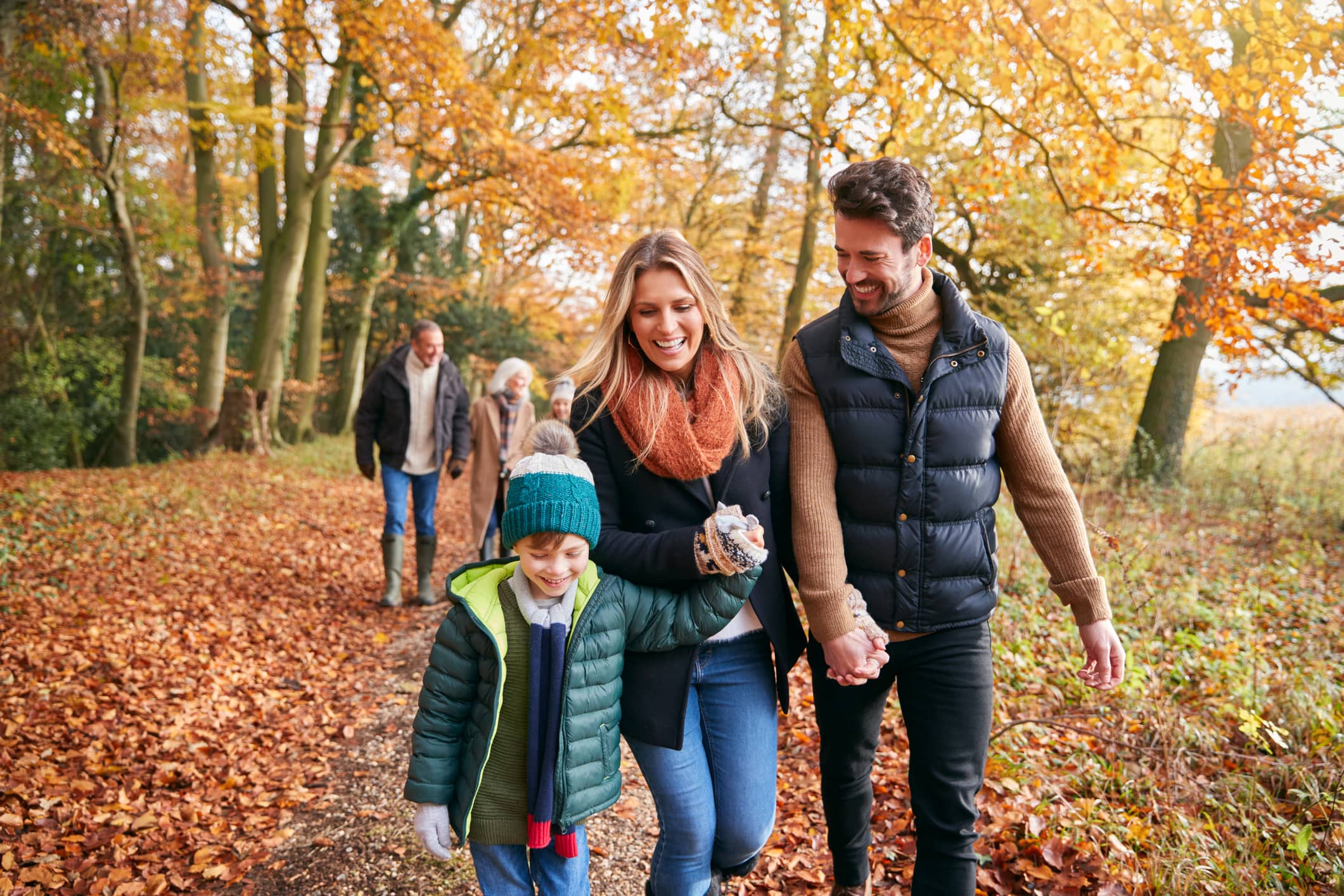 Parents walking hand in hand with their young child along an autumn woodland path.Parents enjoying a countryside walk with their child, reflecting how thoughtful financial gifting can help families plan for the future.