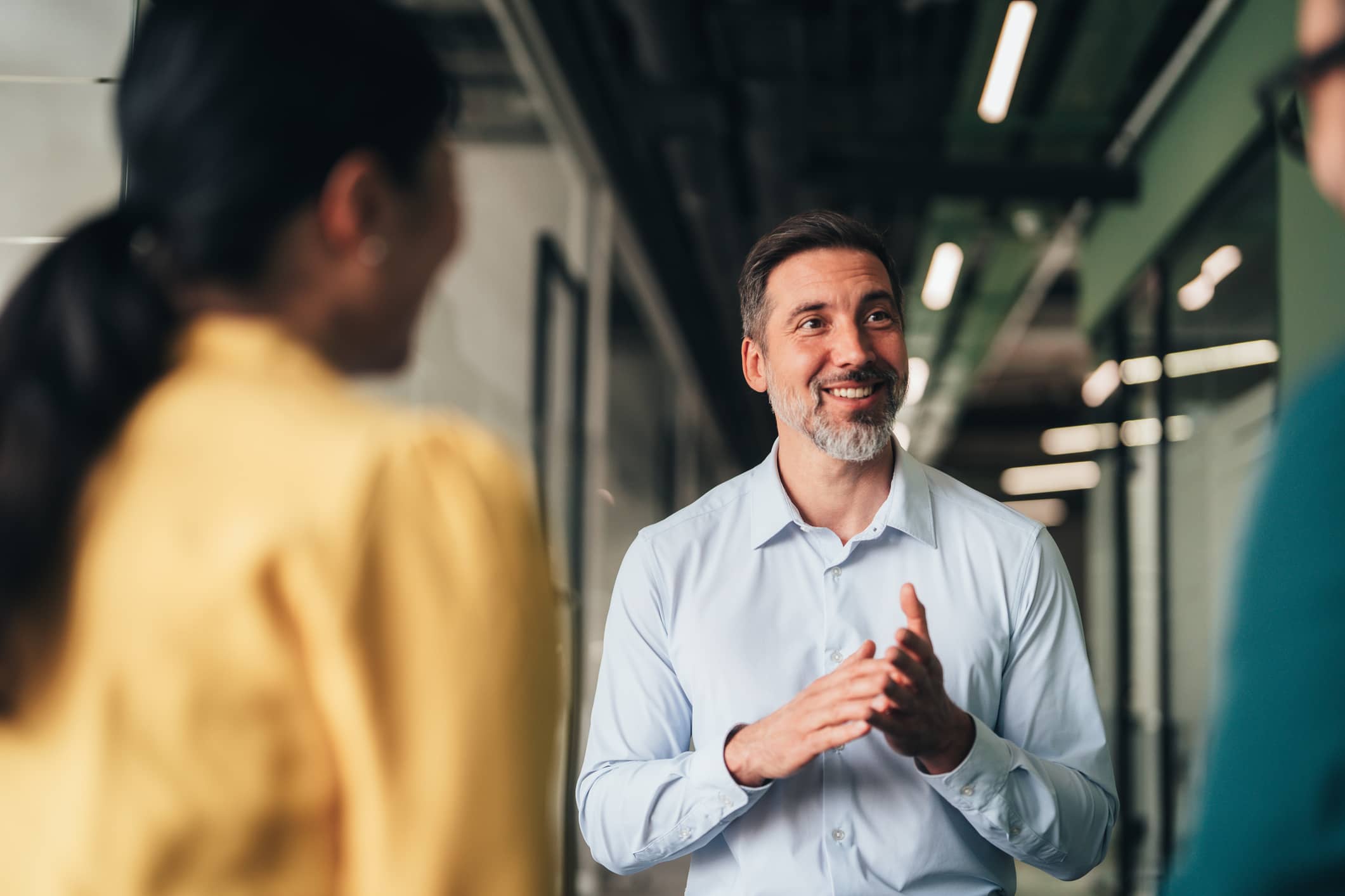 Financial adviser speaking with two people during a meeting in a modern office.