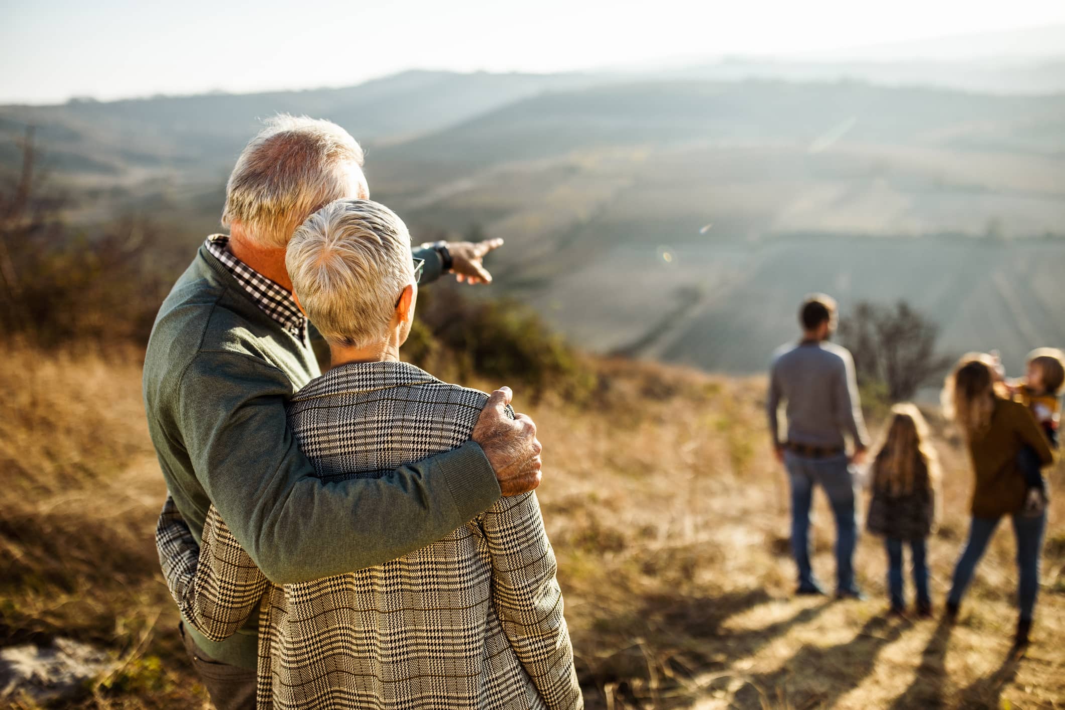 Older couple looking towards younger family members during a countryside walk